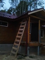 Угол деревянного дома с бордовой крышей и снегозадержателем