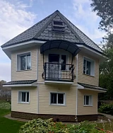 Главный фасад дома с кованым балконом и козырьком