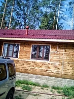 Коттедж с бордовой металлической крышей и водостоком