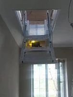 Моторизованная лестница на чердак, частично раскрытая, видны ступени и мотор