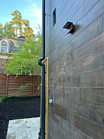 Тёмный фасад дома с водостоком и настенным светильником