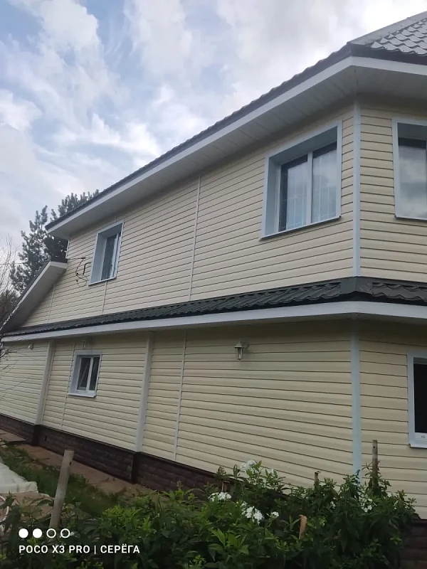 Боковой вид дома с бежевым виниловым сайдингом и серой кровлей
