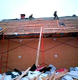Монтажники устанавливают обрешётку на крыше кирпичного дома