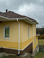 Угол дома с белым водостоком Döcke Premium ПВХ на жёлтой стене