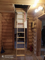 Раскладная чердачная лестница в бревенчатом доме в разложенном состоянии