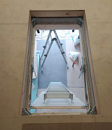 Вид сверху на сложенную чердачную лестницу через проём люка