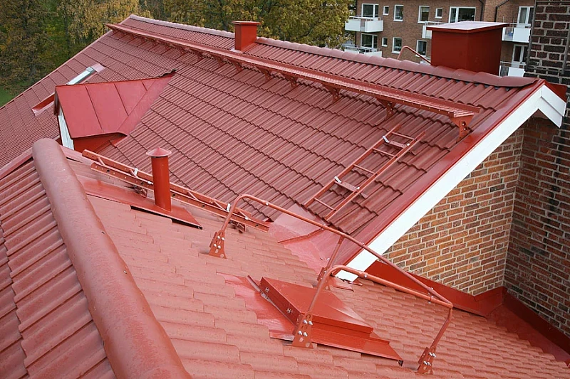 Красная кровля из металлочерепицы с системой кровельных лестниц и переходных мостиков