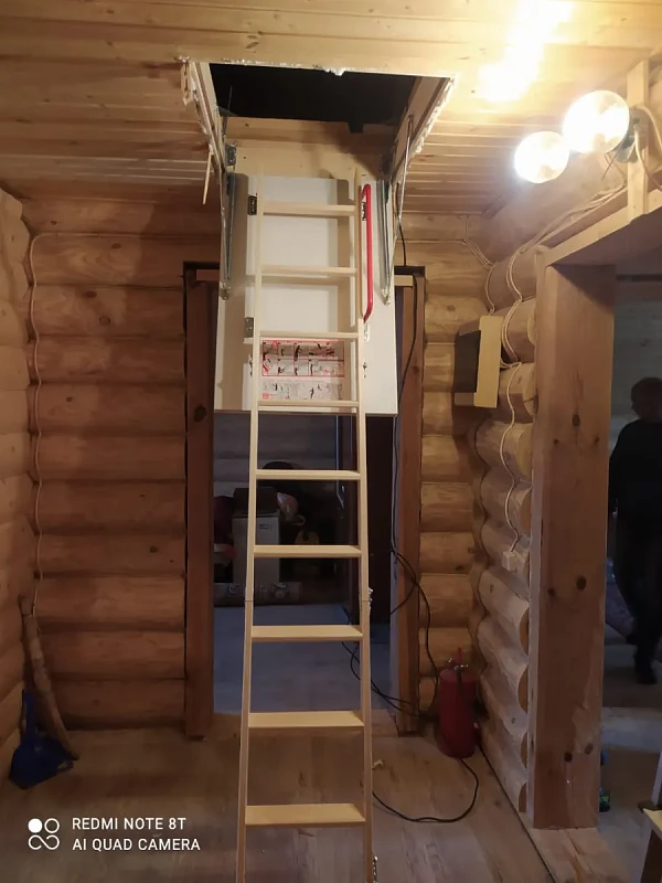 Раскладная чердачная лестница в бревенчатом доме в разложенном состоянии