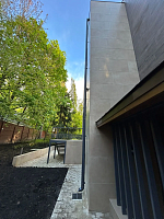 Боковой вид дома с вертикальной водосточной трубой и мощёной дорожкой