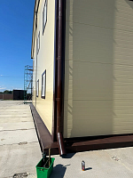 Угол здания с водосточной трубой и отводом у земли